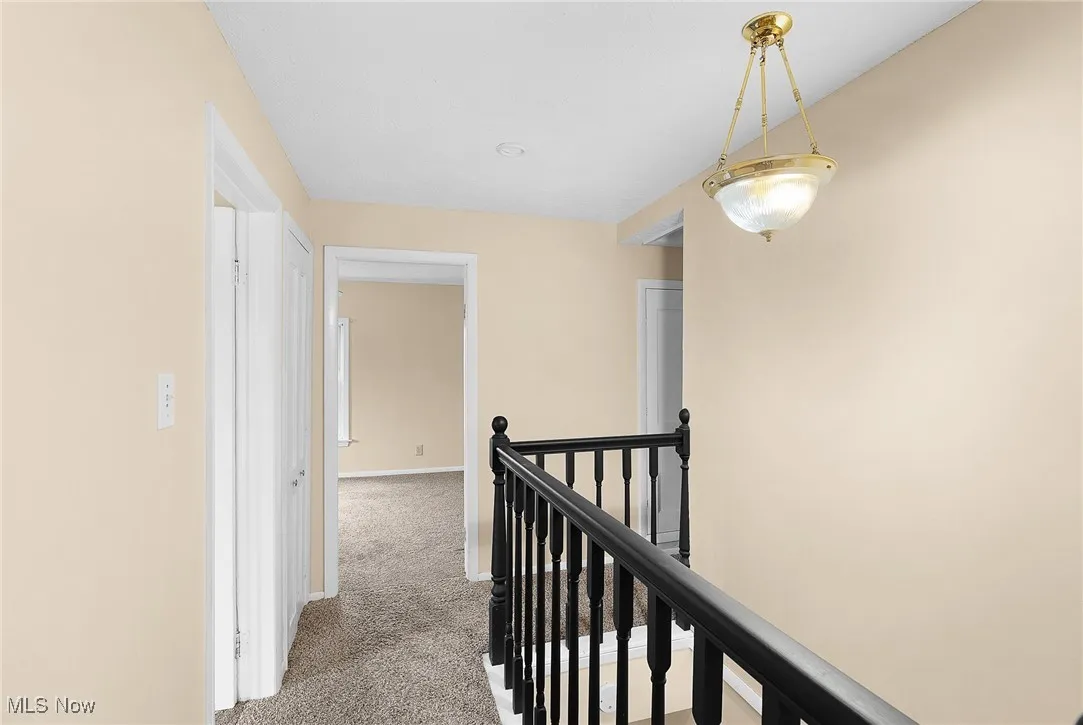 Hallway with an upstairs landing and light carpet