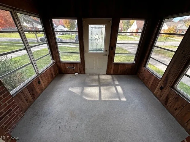 Unfurnished sunroom with wooden walls and carpet