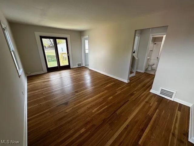 Empty room with dark wood-style flooring and stairs