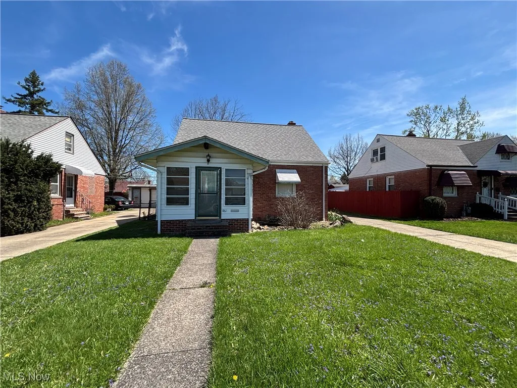 Bungalow with a front yard, a shingled roof, entry steps, and brick siding