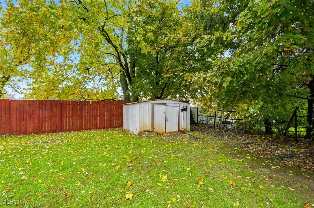 Fenced backyard featuring a shed