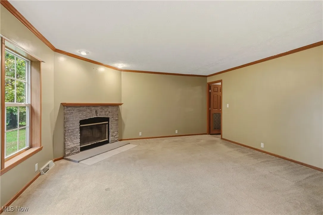 Family room featuring a brick fireplace, ornamental molding, and carpet floors