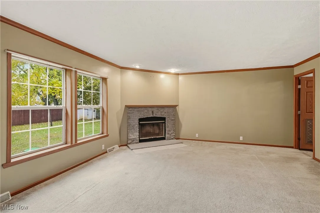 Family room with a brick fireplace, ornamental molding, and carpet floors