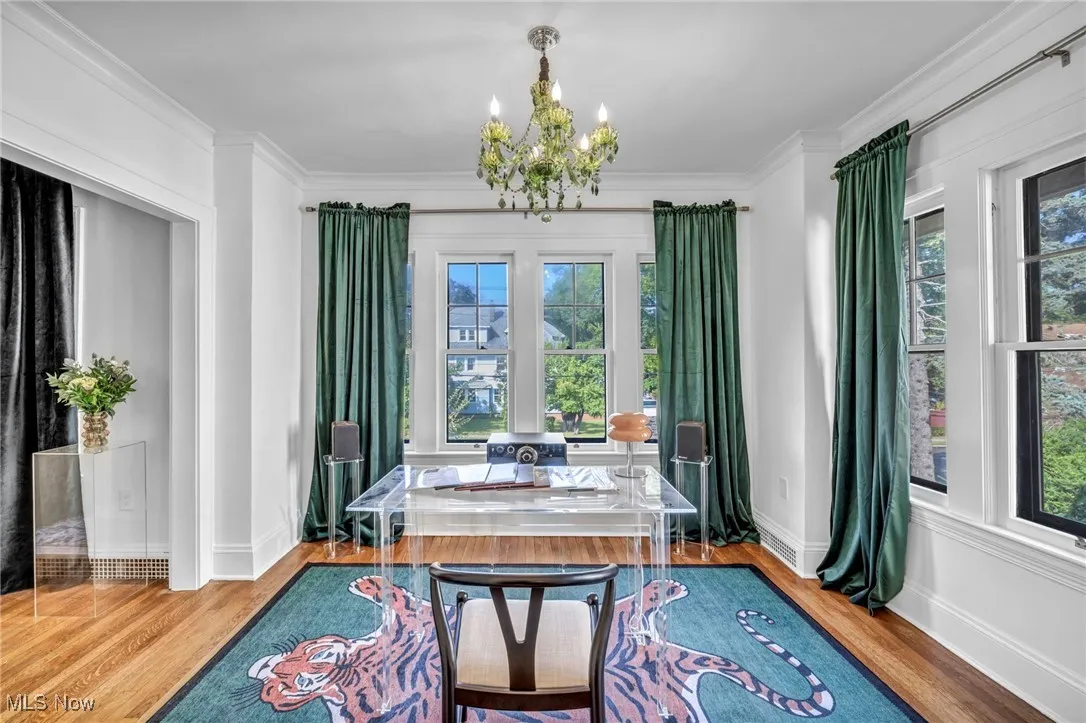 Home office with wood finished floors, ornamental molding, and a chandelier