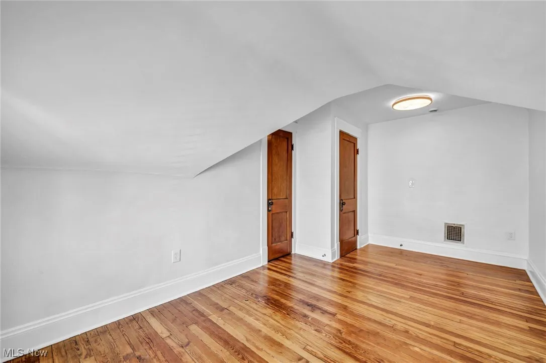 Additional living space with light wood-style floors and lofted ceiling