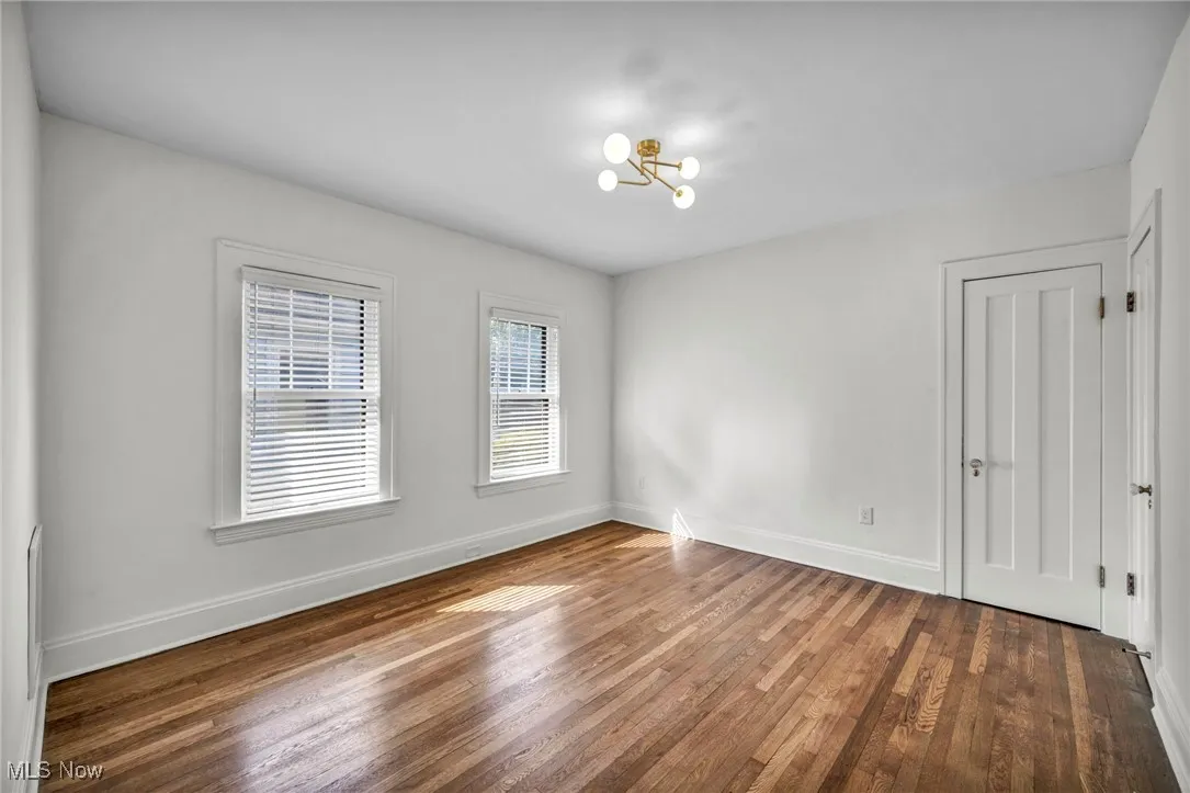 Unfurnished room featuring wood finished floors and a chandelier