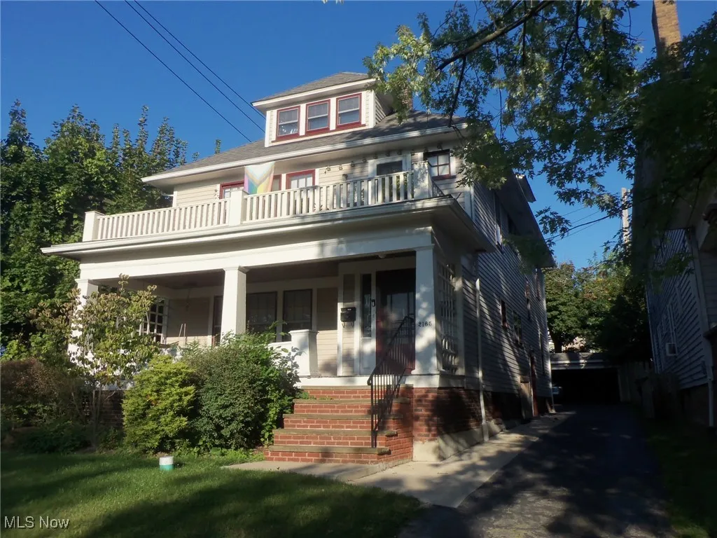 American foursquare style home with a porch, a balcony, and a front lawn
