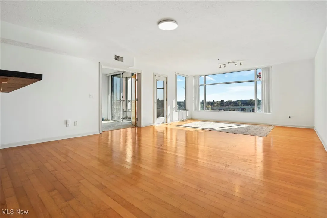 Unfurnished living room featuring wood-type flooring and baseboards
