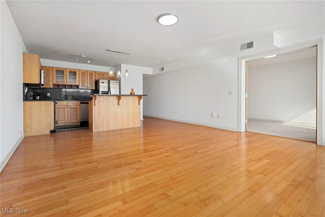 Kitchen featuring a breakfast bar, glass insert cabinets, light wood finished floors, and dark countertops