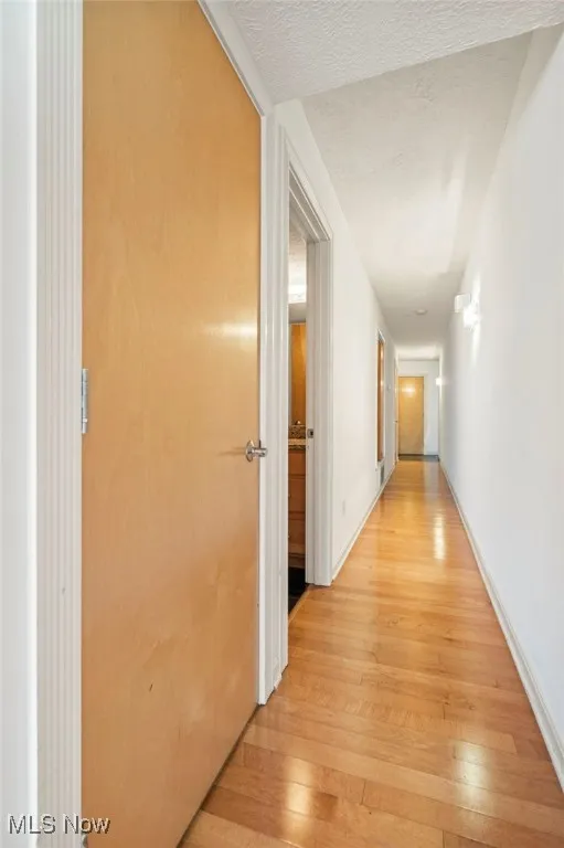 Corridor featuring light wood-style floors and a textured ceiling