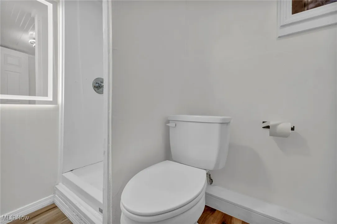 Bathroom featuring wood finished floors and a stall shower