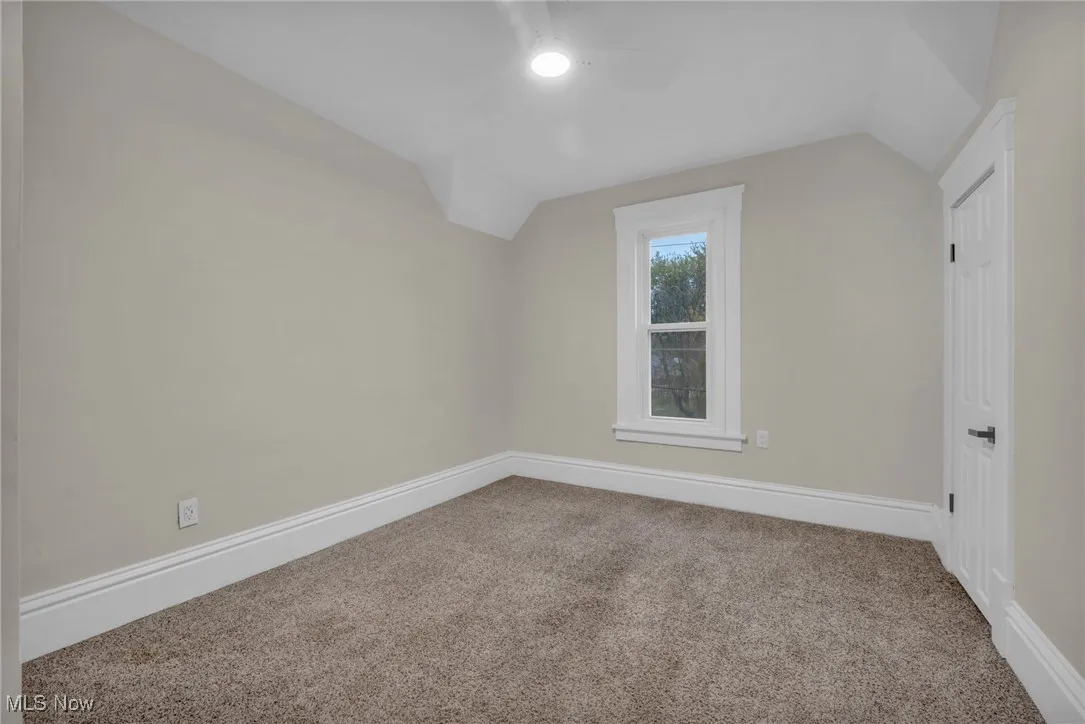 Additional living space with vaulted ceiling, light colored carpet, and ceiling fan