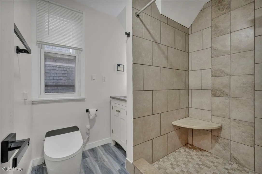 Bathroom with a stall shower, wood finished floors, and vanity