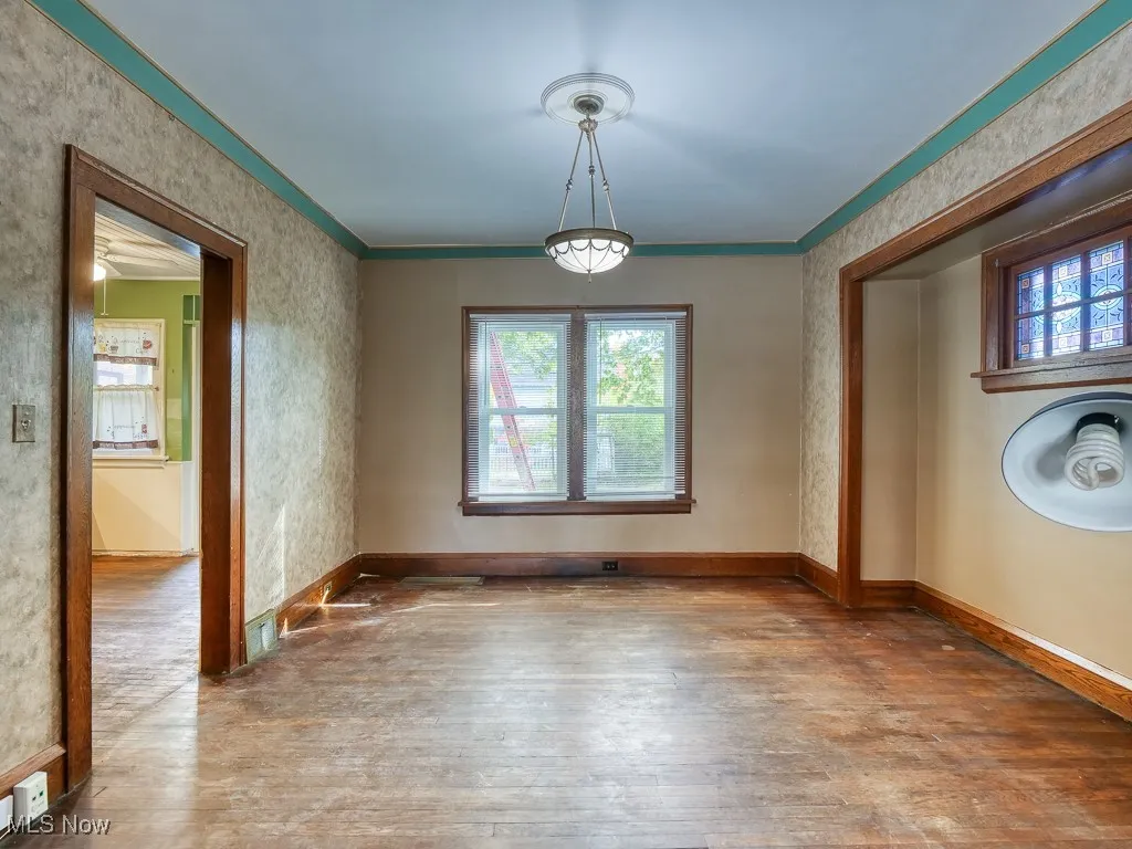Unfurnished dining area featuring hardwood / wood-style flooring, wallpapered walls, and ornamental molding