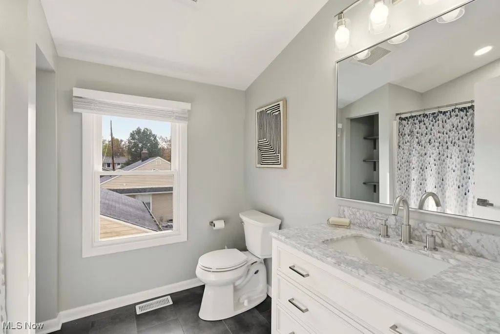 Full bathroom featuring vanity, curtained shower, and dark tile patterned floors