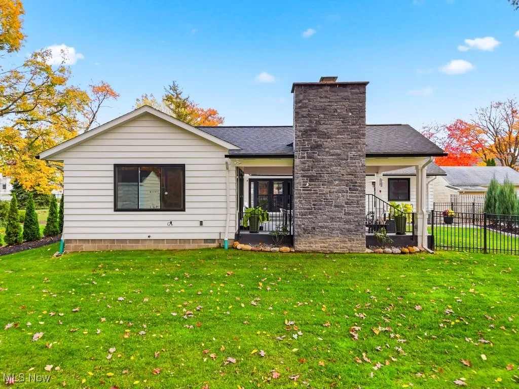 Rear view of property with roof with shingles, a chimney, and a patio