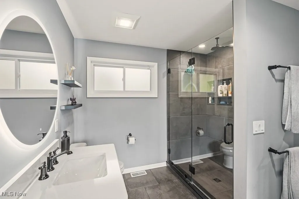 Bathroom featuring a shower stall, vanity, dark tile patterned flooring, and recessed lighting