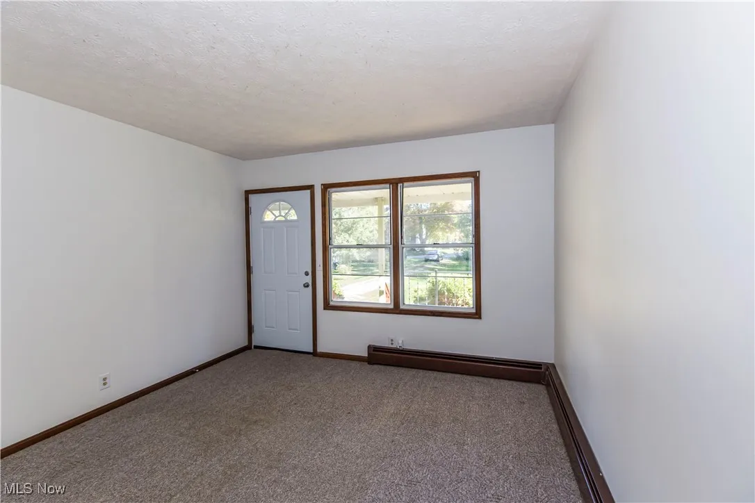 Entrance foyer featuring carpet floors, baseboard heating, and a textured ceiling