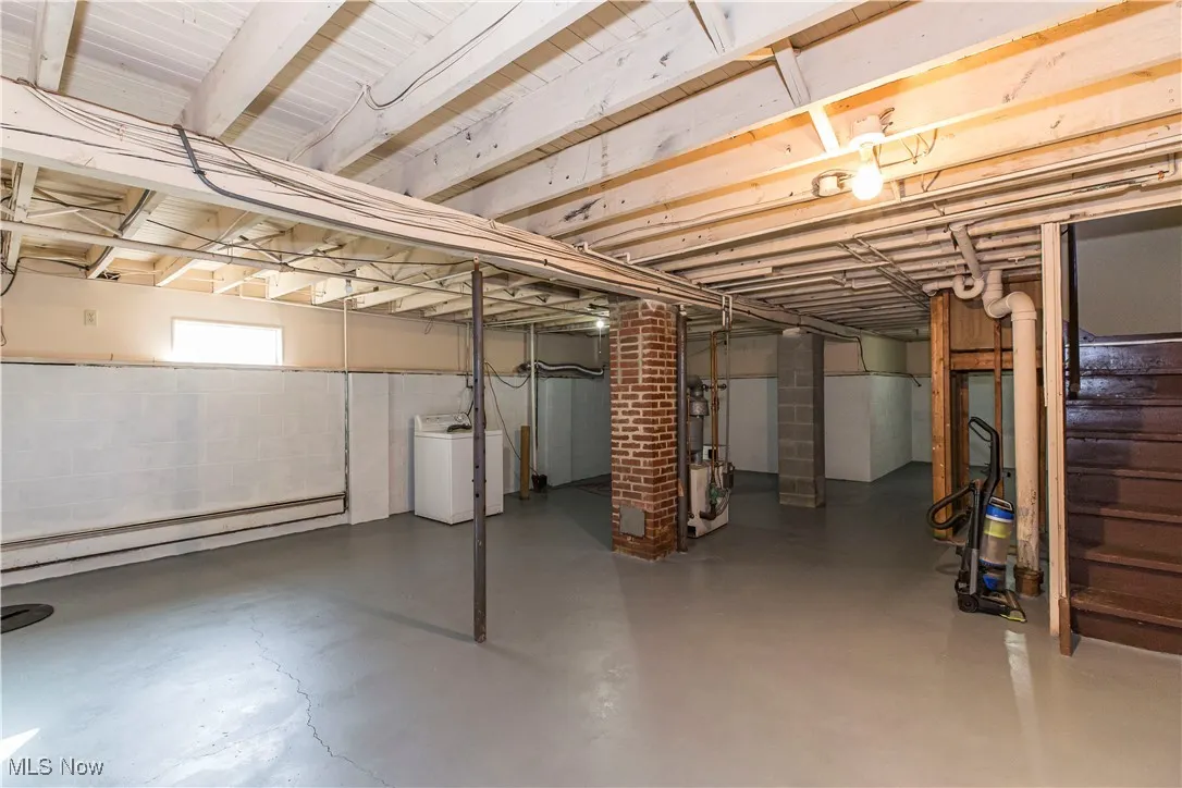 Below grade area featuring washer / dryer, a baseboard heating unit, and stairs