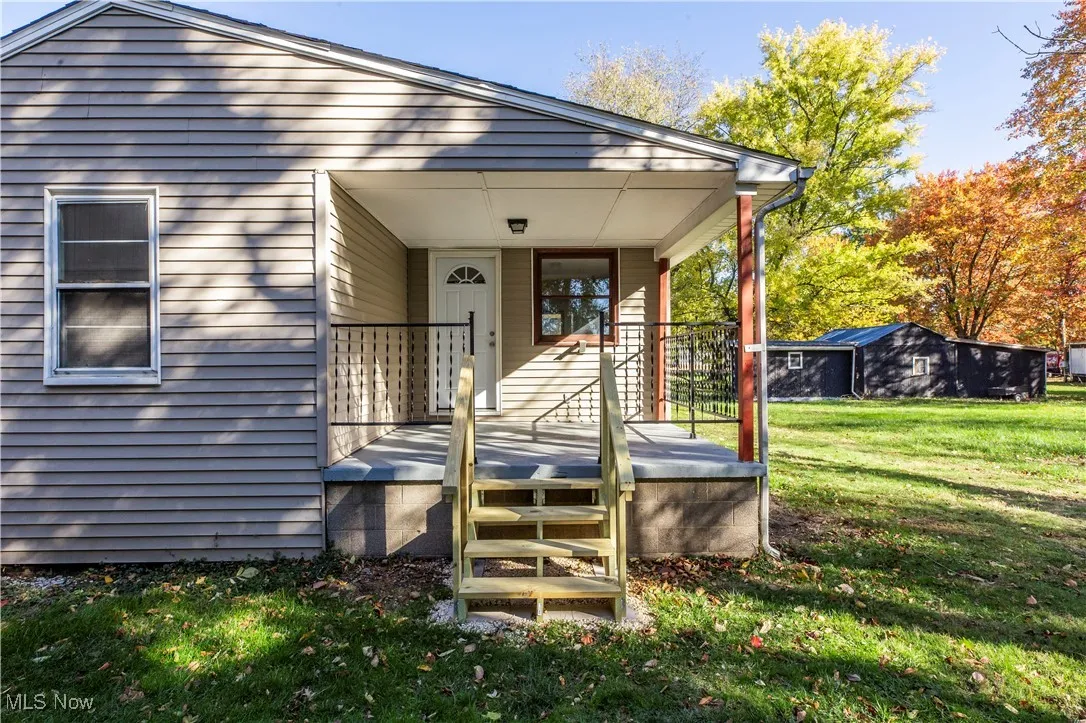 Doorway to property with a lawn and covered porch