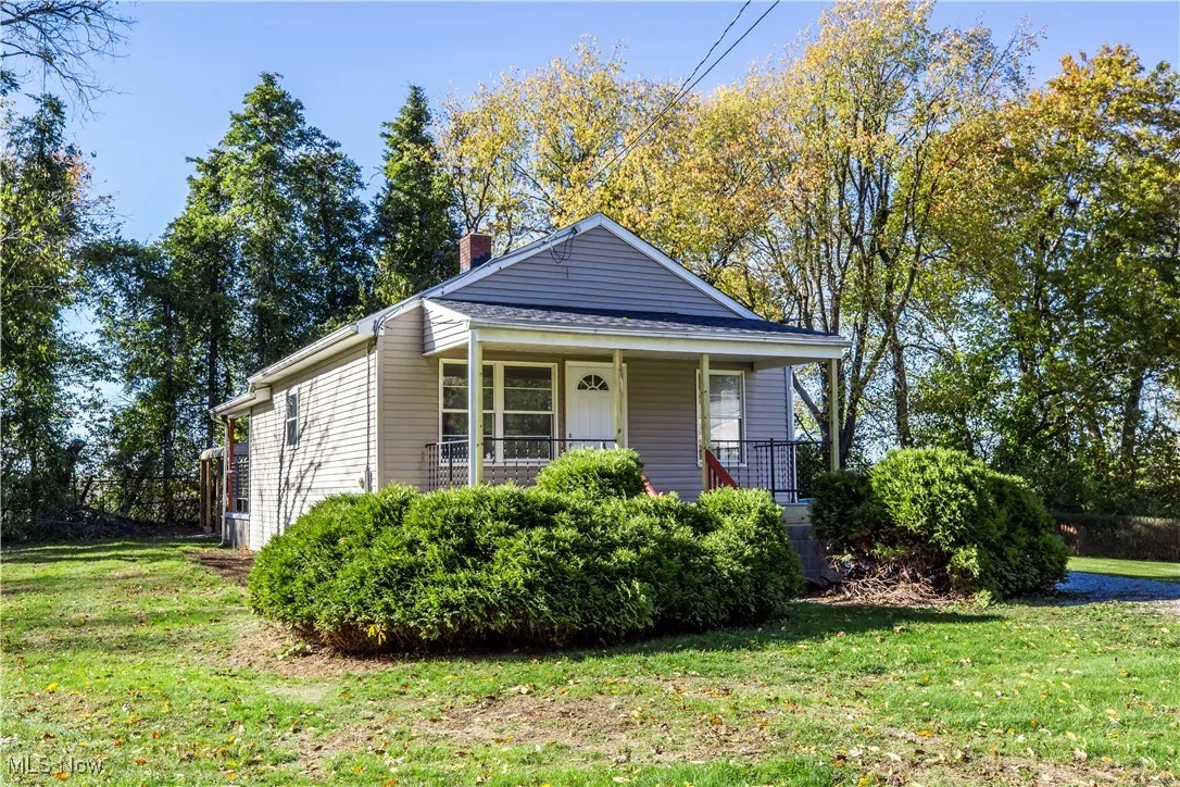 View of front of house featuring a front lawn, a porch, and a chimney