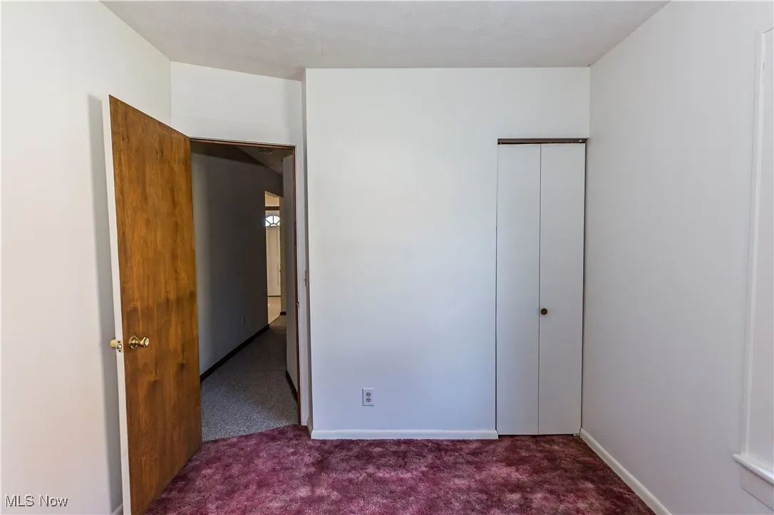 Unfurnished bedroom featuring dark carpet and a closet