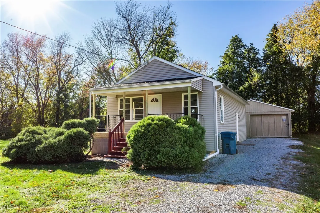 Bungalow-style home featuring a porch, an outbuilding, a detached garage, and a front yard