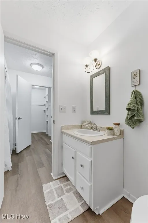 Bathroom featuring a textured ceiling, light wood-type flooring, vanity, and a chandelier