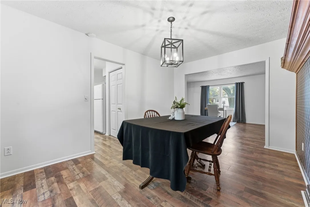 Dining area with a textured ceiling and dark wood-type flooring