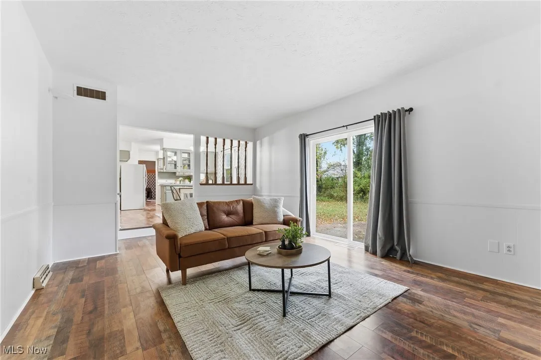 Living area with dark wood finished floors, a textured ceiling, and a baseboard heating unit