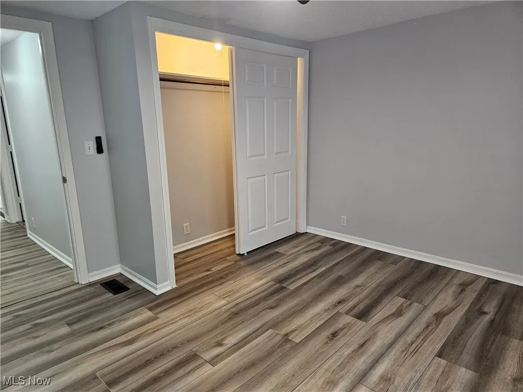 Unfurnished bedroom with wood finished floors and a closet