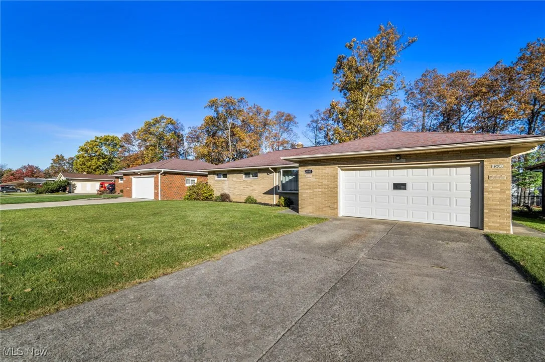 Ranch-style house with driveway, an attached garage, and a front lawn