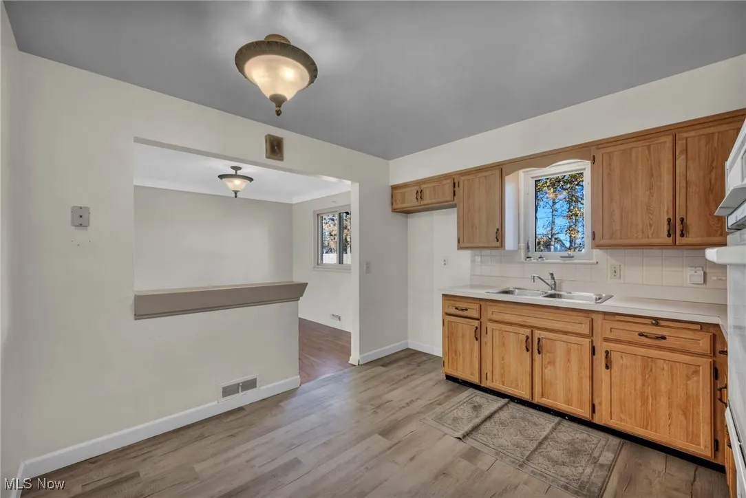 Kitchen featuring light wood-style flooring, light countertops, decorative backsplash, and light brown cabinetry
