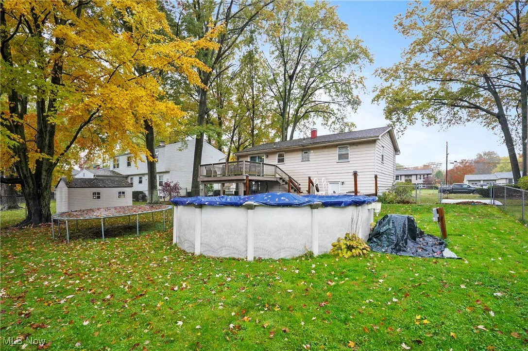Rear view of house featuring a covered pool, stairway, a chimney, and a trampoline