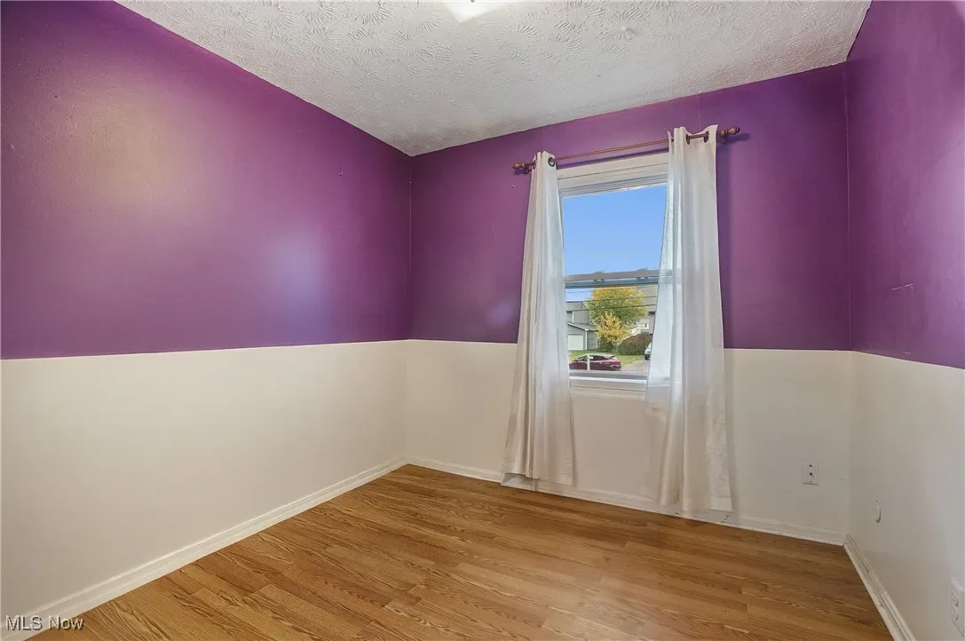 Empty room featuring light wood finished floors and a textured ceiling