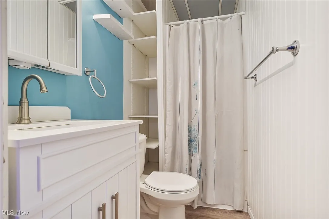 Bathroom featuring vanity, curtained shower, and wood finished floors