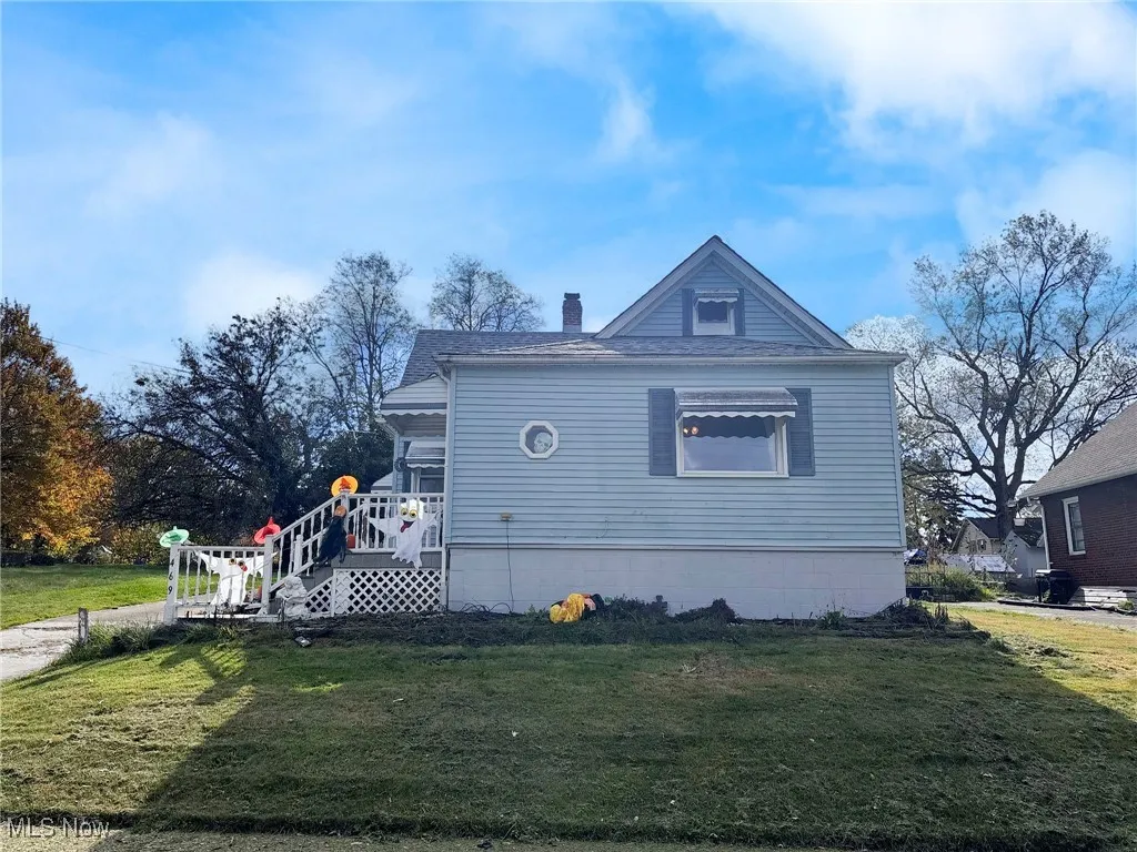 View of home's exterior featuring a lawn, a wooden deck, a chimney, and roof with shingles