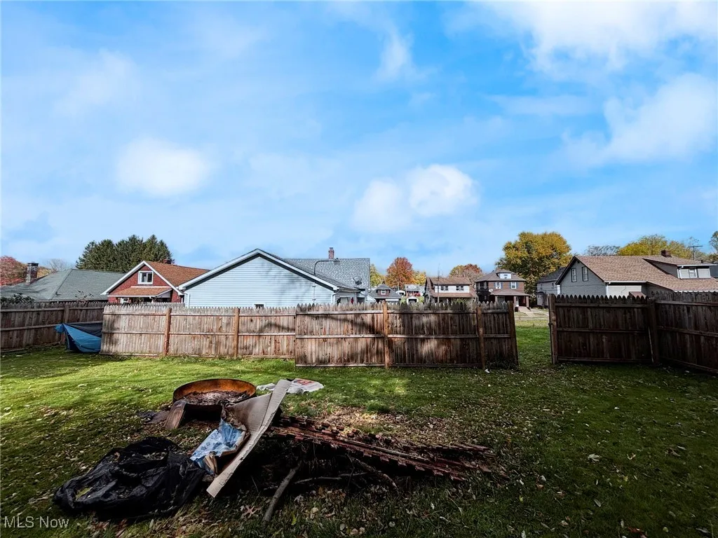 Fenced backyard featuring an outdoor fire pit and a residential view