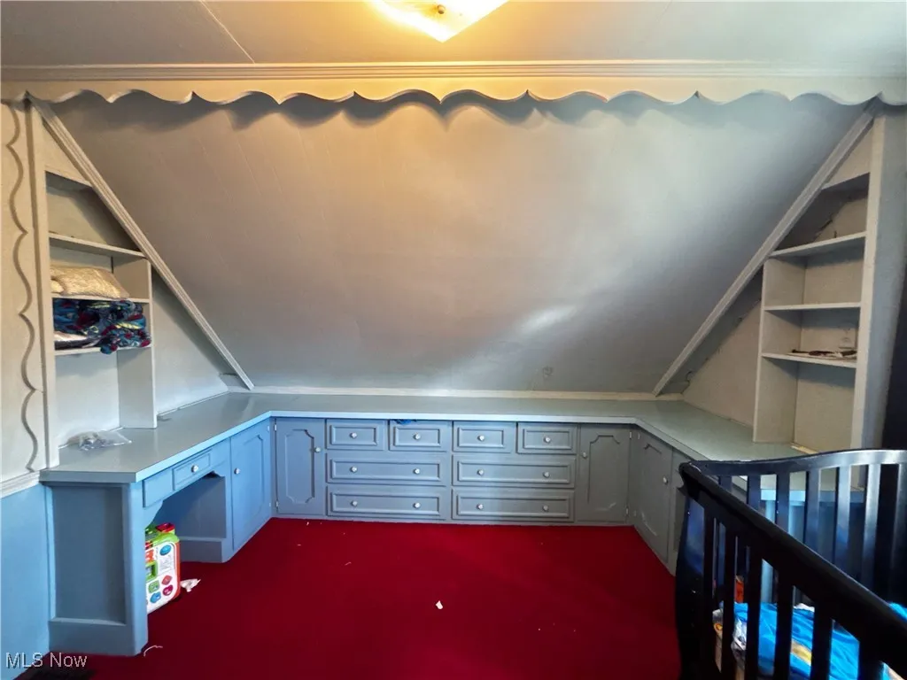 Additional living space with lofted ceiling and dark carpet