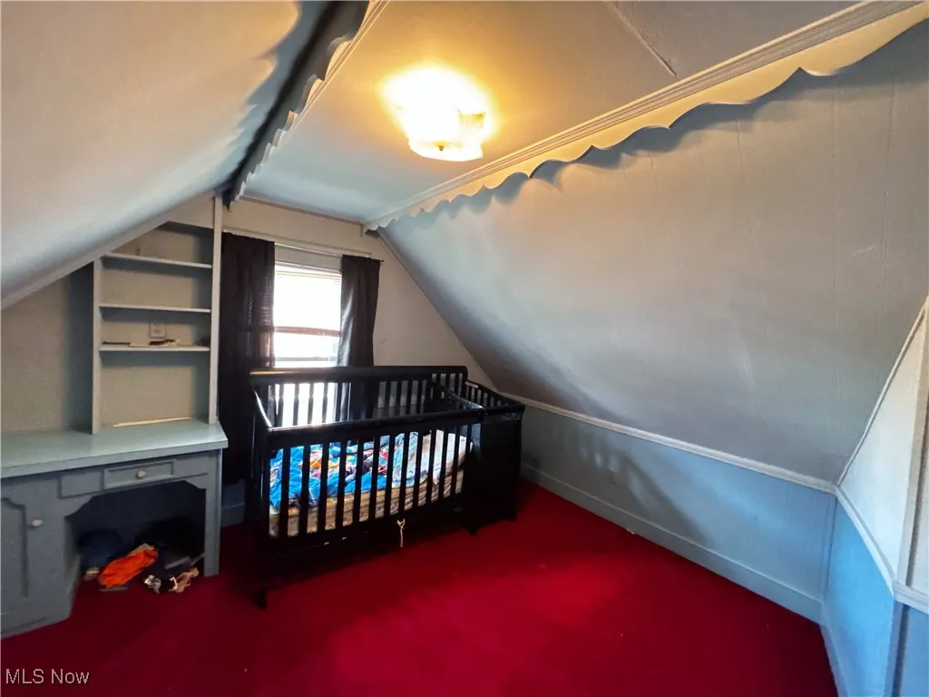 Additional living space with vaulted ceiling and dark colored carpet