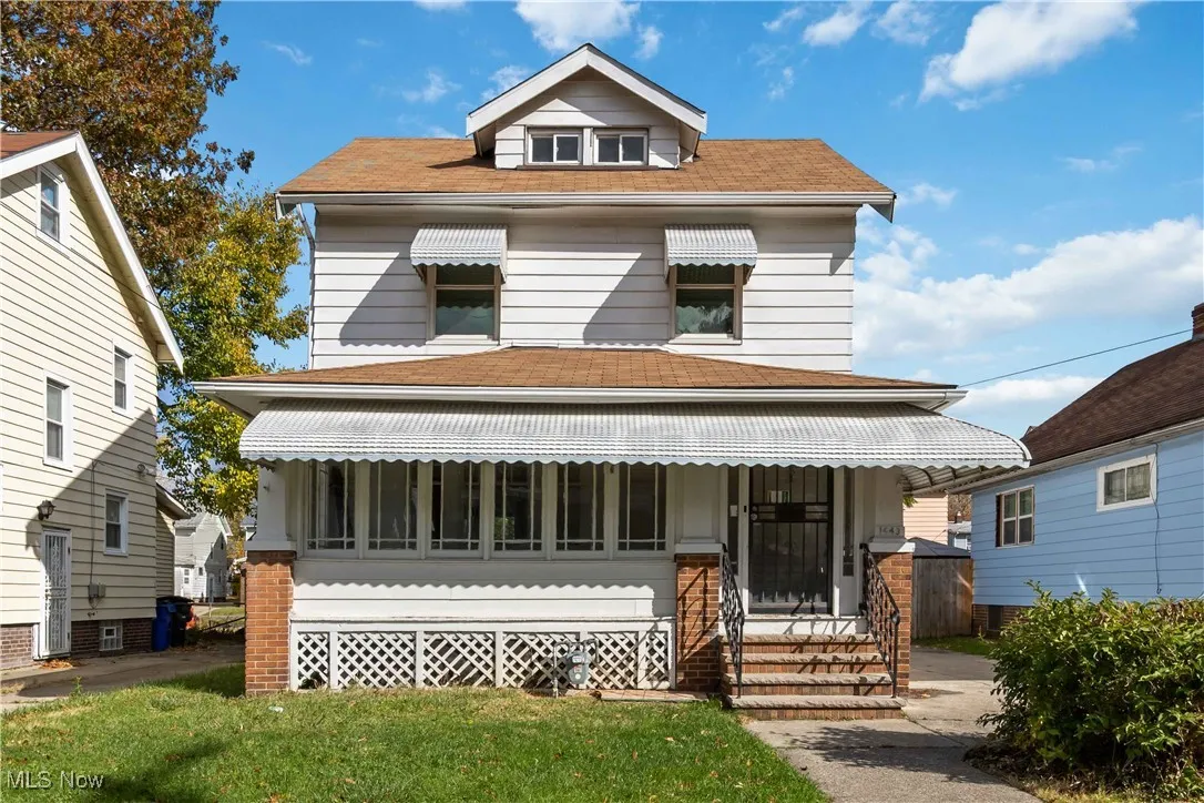 American foursquare style home with a porch, roof with shingles, and a front yard
