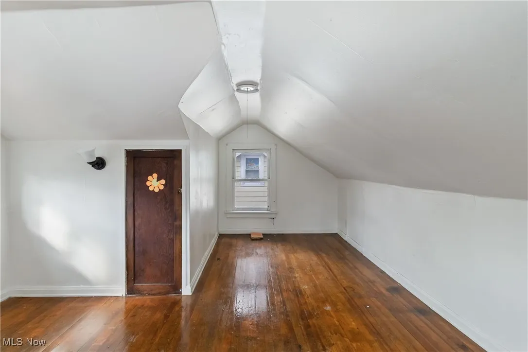 Additional living space featuring dark wood-style flooring and vaulted ceiling
