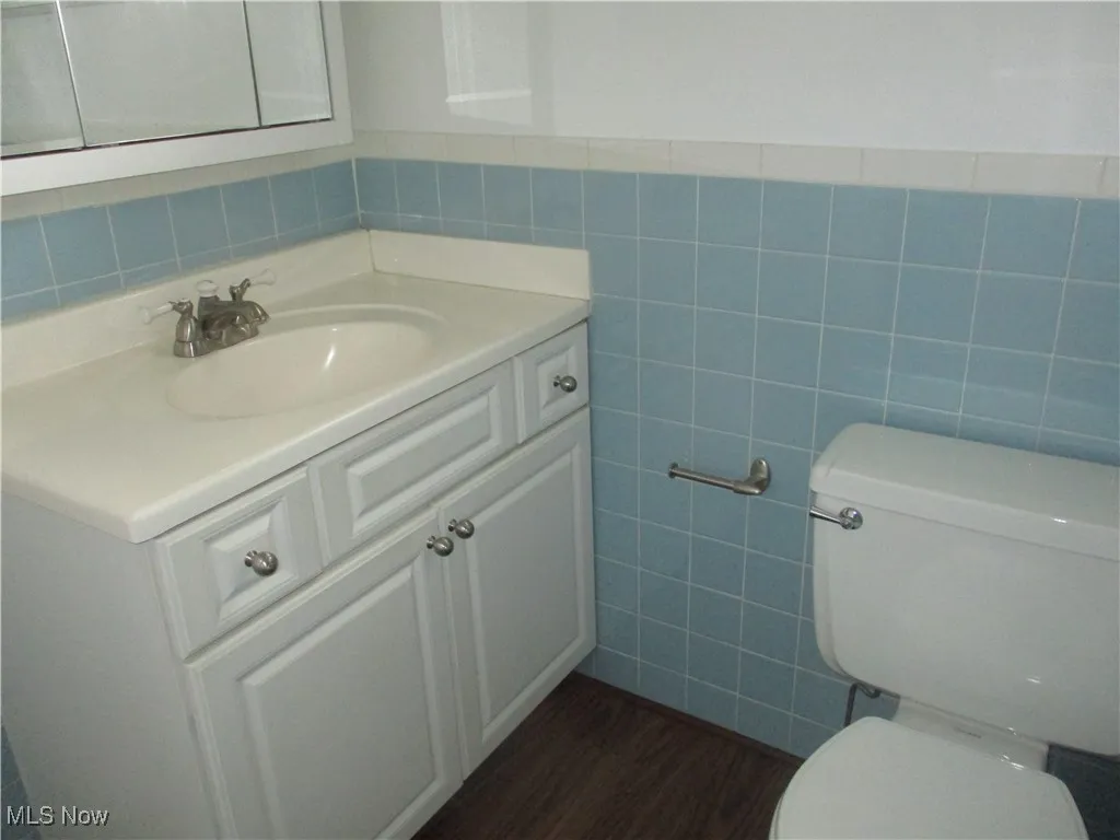 Bathroom featuring toilet, tile walls, hardwood / wood-style flooring, and large vanity