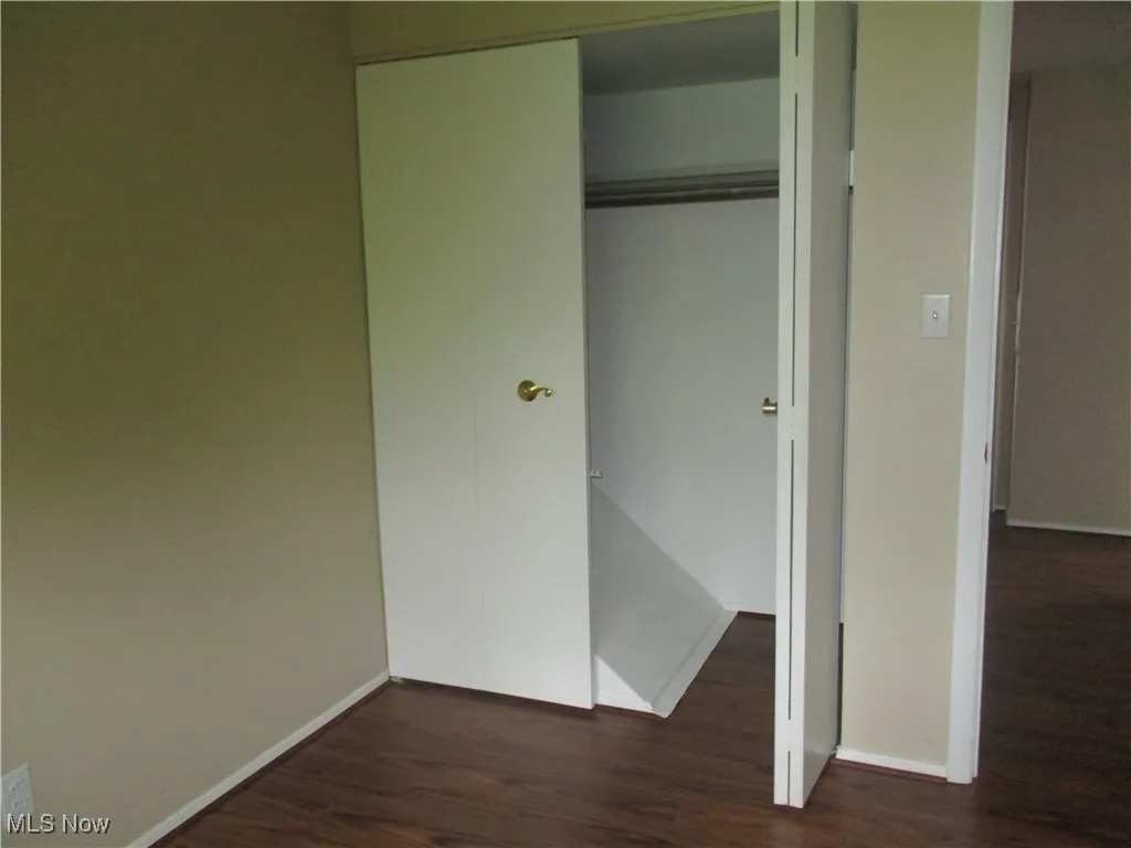 Featuring dark hardwood/ wood style flooring and a closet
