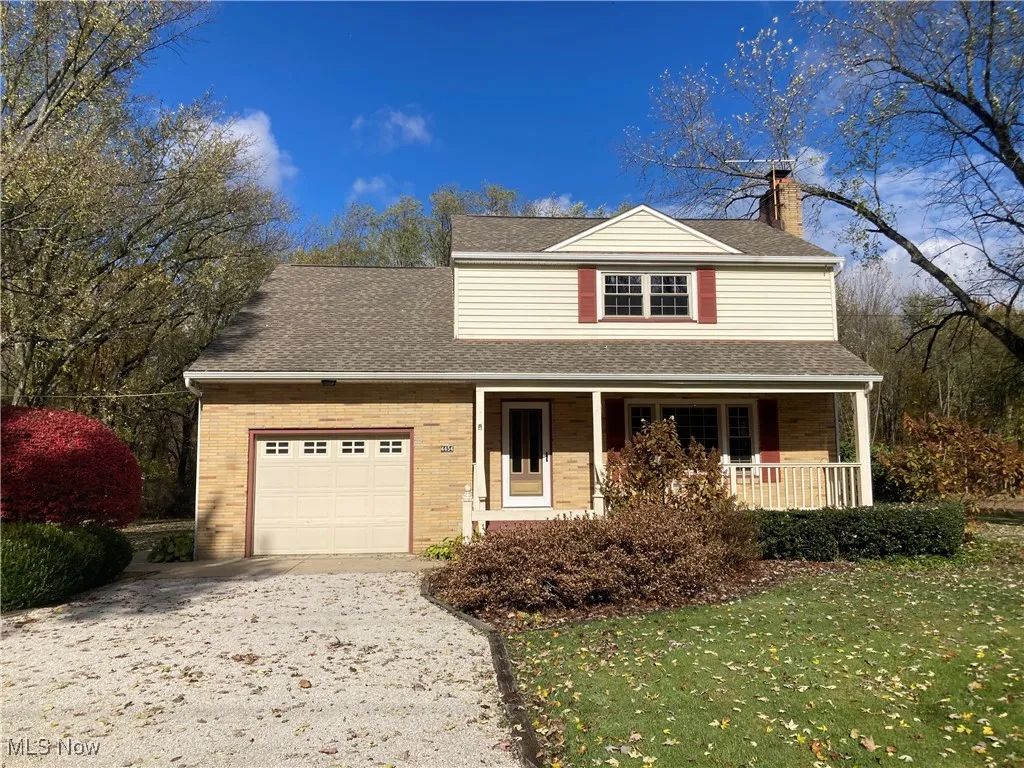 Traditional-style home featuring covered porch, roof with shingles, a chimney, driveway, and brick siding