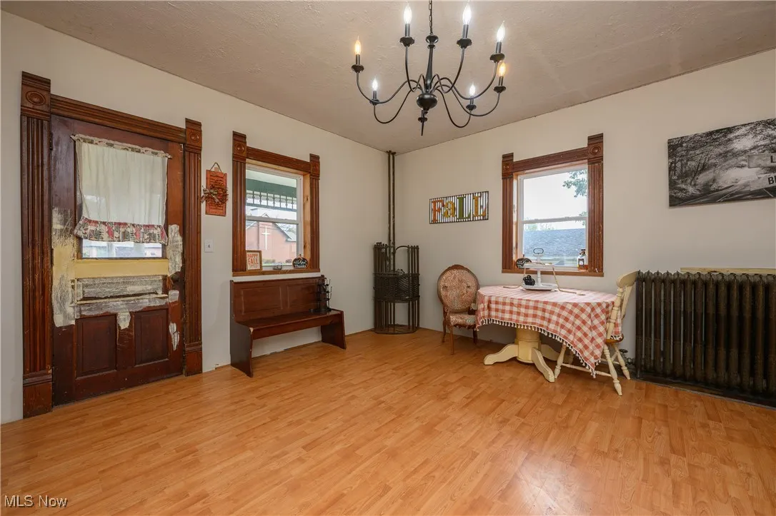 Dining space with radiator, light wood finished floors, a chandelier, and a textured ceiling