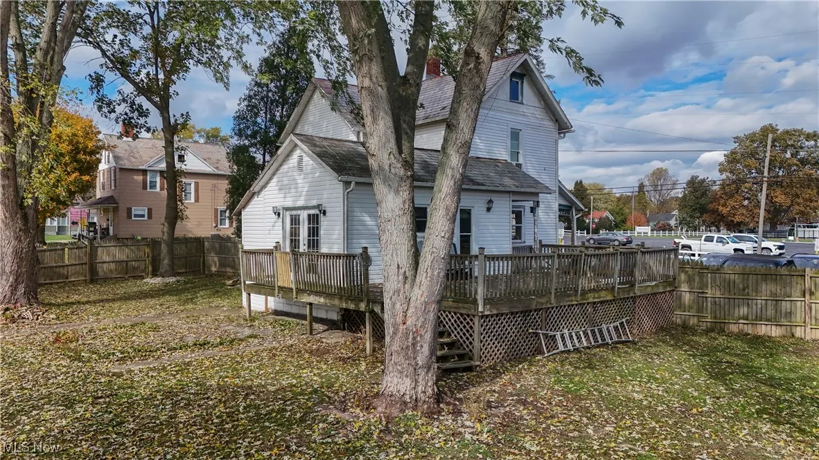 Back of property with a fenced backyard, a deck, and roof with shingles