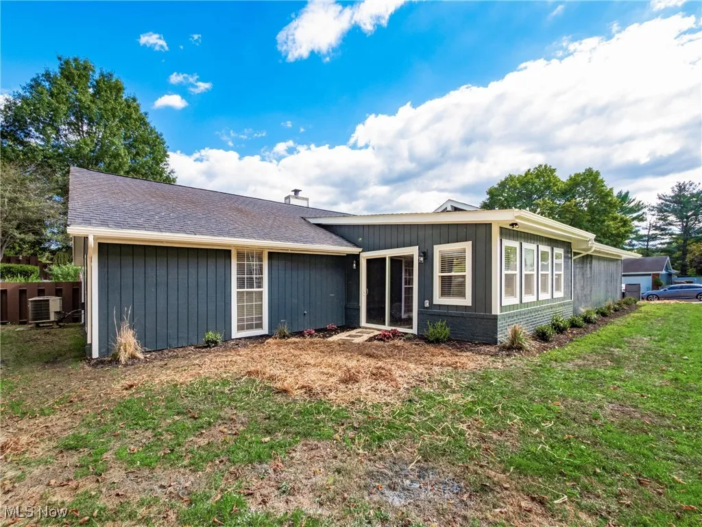 View of front of house featuring a front lawn, roof with shingles, and brick siding