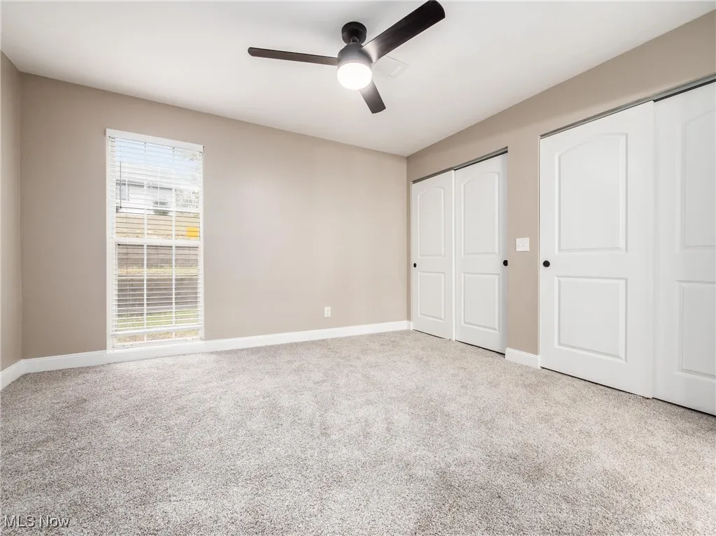 Unfurnished bedroom with multiple closets, light colored carpet, and ceiling fan