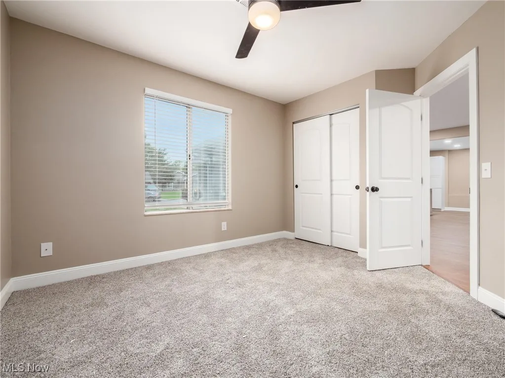Unfurnished bedroom featuring light colored carpet, a closet, and a ceiling fan